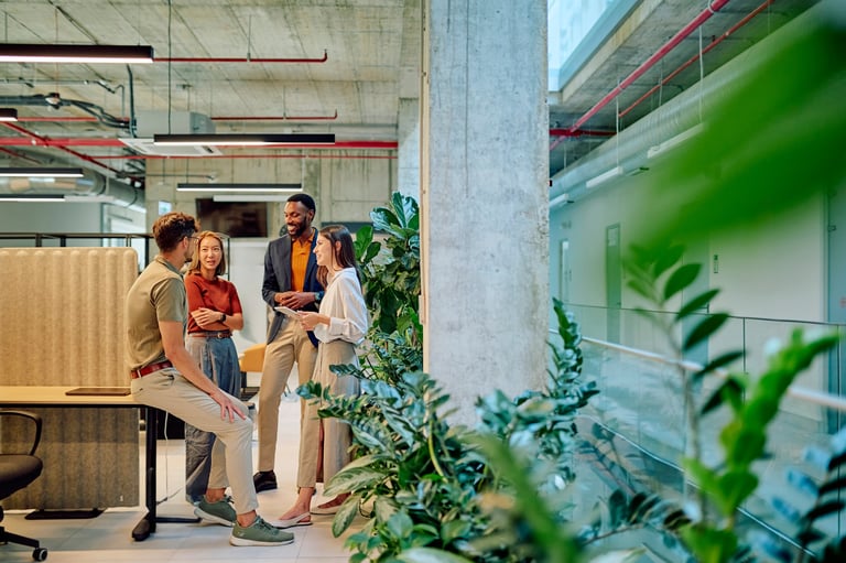 Diverse group of businesspeople engaged in collaborative work with plants in modern office